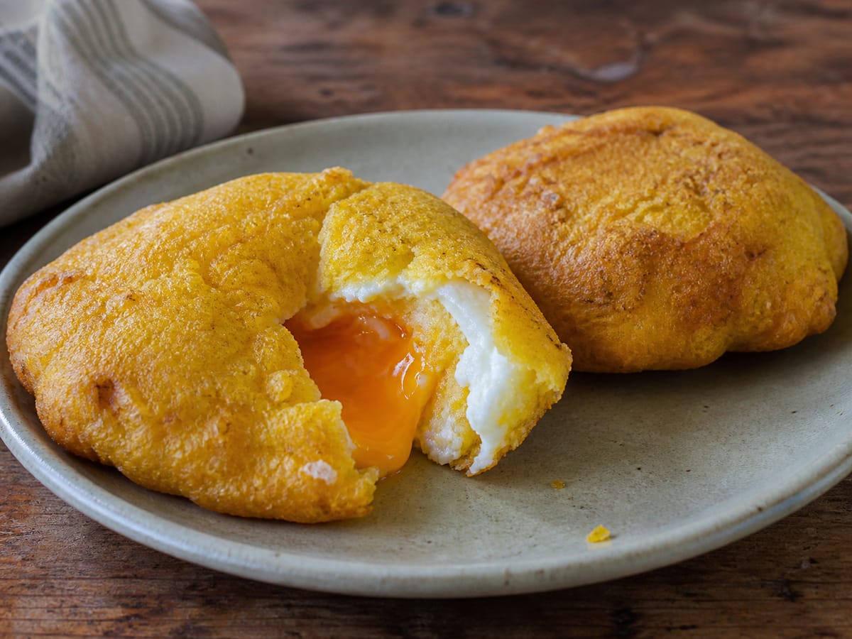 Arepa de huevo costeña abierta con el huevo visible en su interior